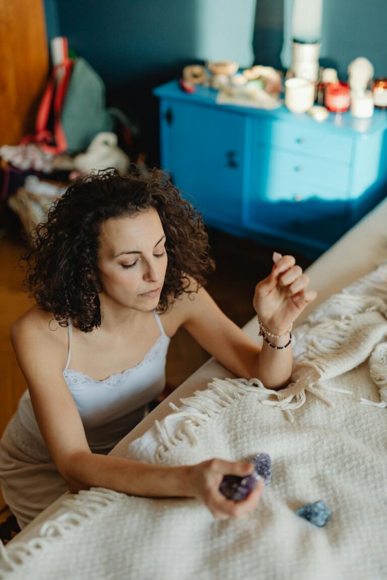 A woman practices meditation with healing crystals indoors, creating a calming atmosphere.